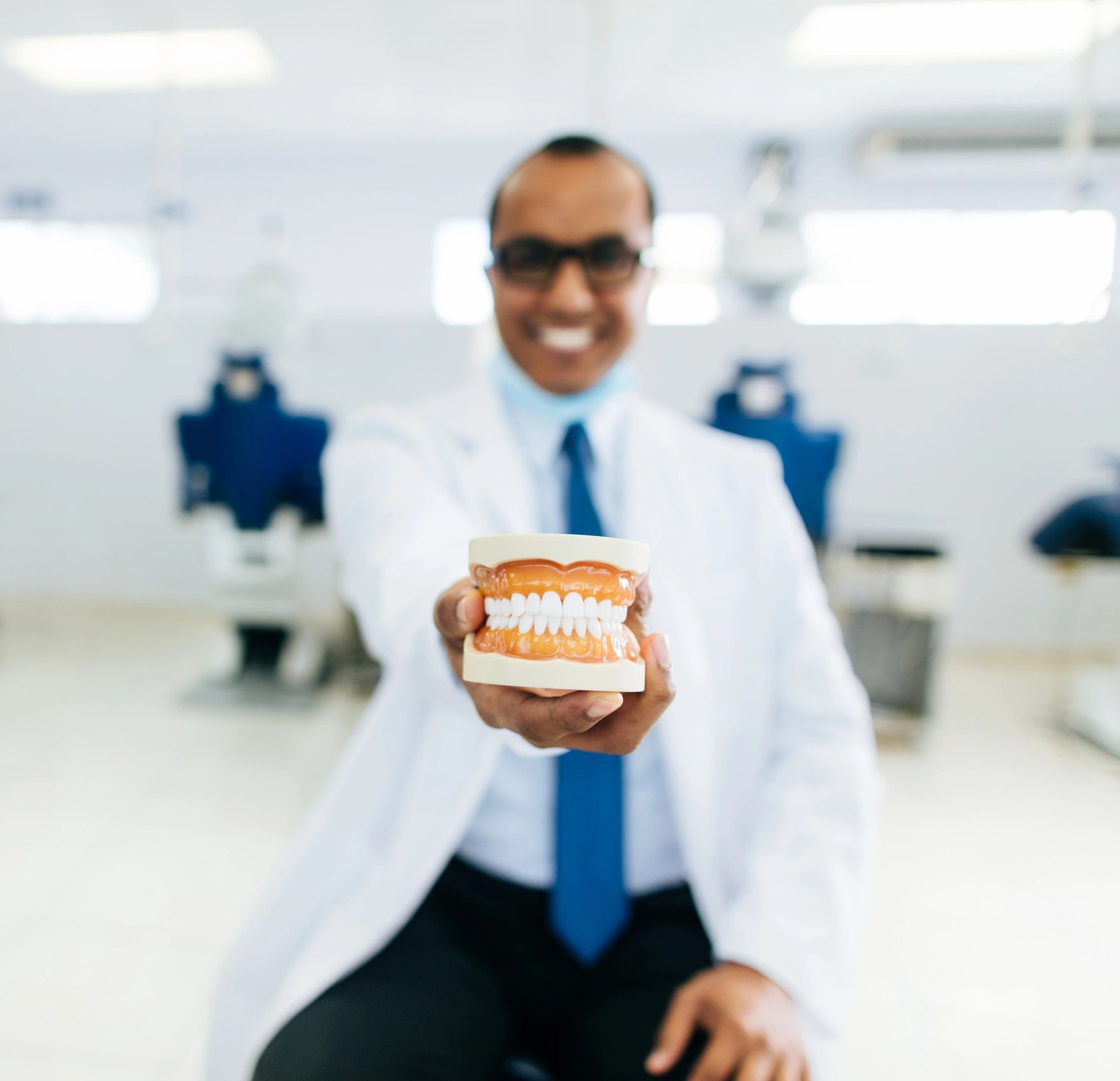 Dentist holding a complete denture during a consultation