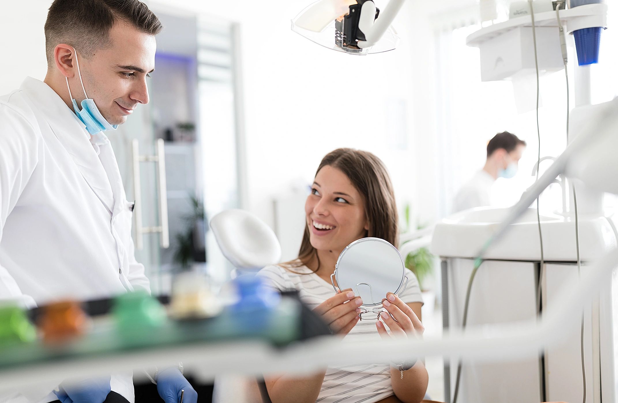Patient smiling and checking her teeth after dental treatment