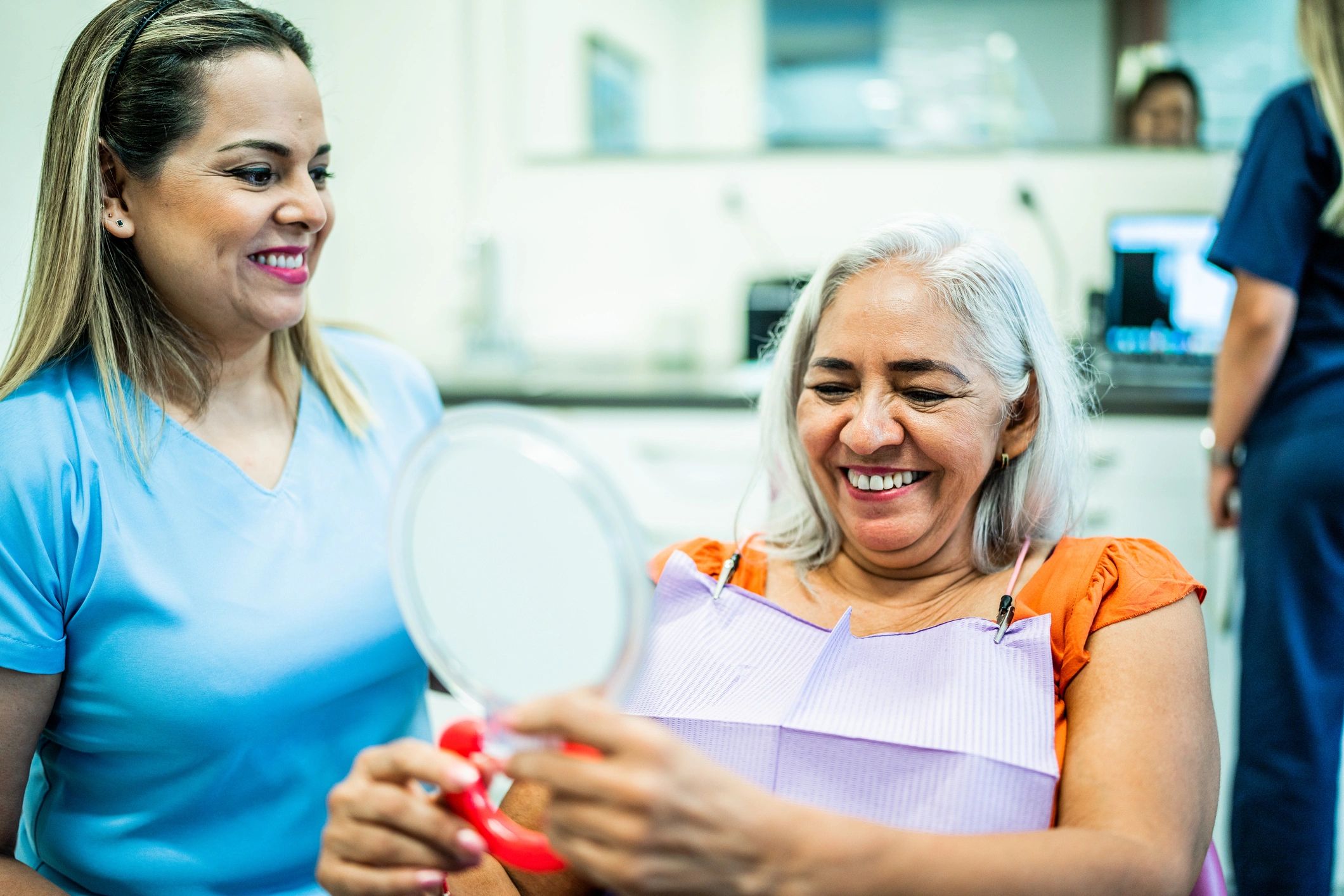 Patient reviewing her smile in a mirror at a dental visit